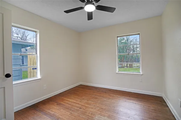 a view of an empty room with wooden floor and a window