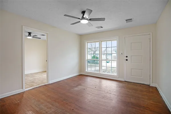 a view of an empty room with wooden floor and a window