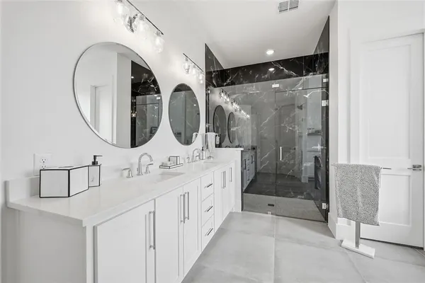 a bathroom with a double vanity sink mirror and shower