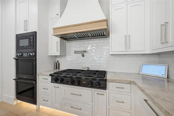 a kitchen with white cabinets and black appliances
