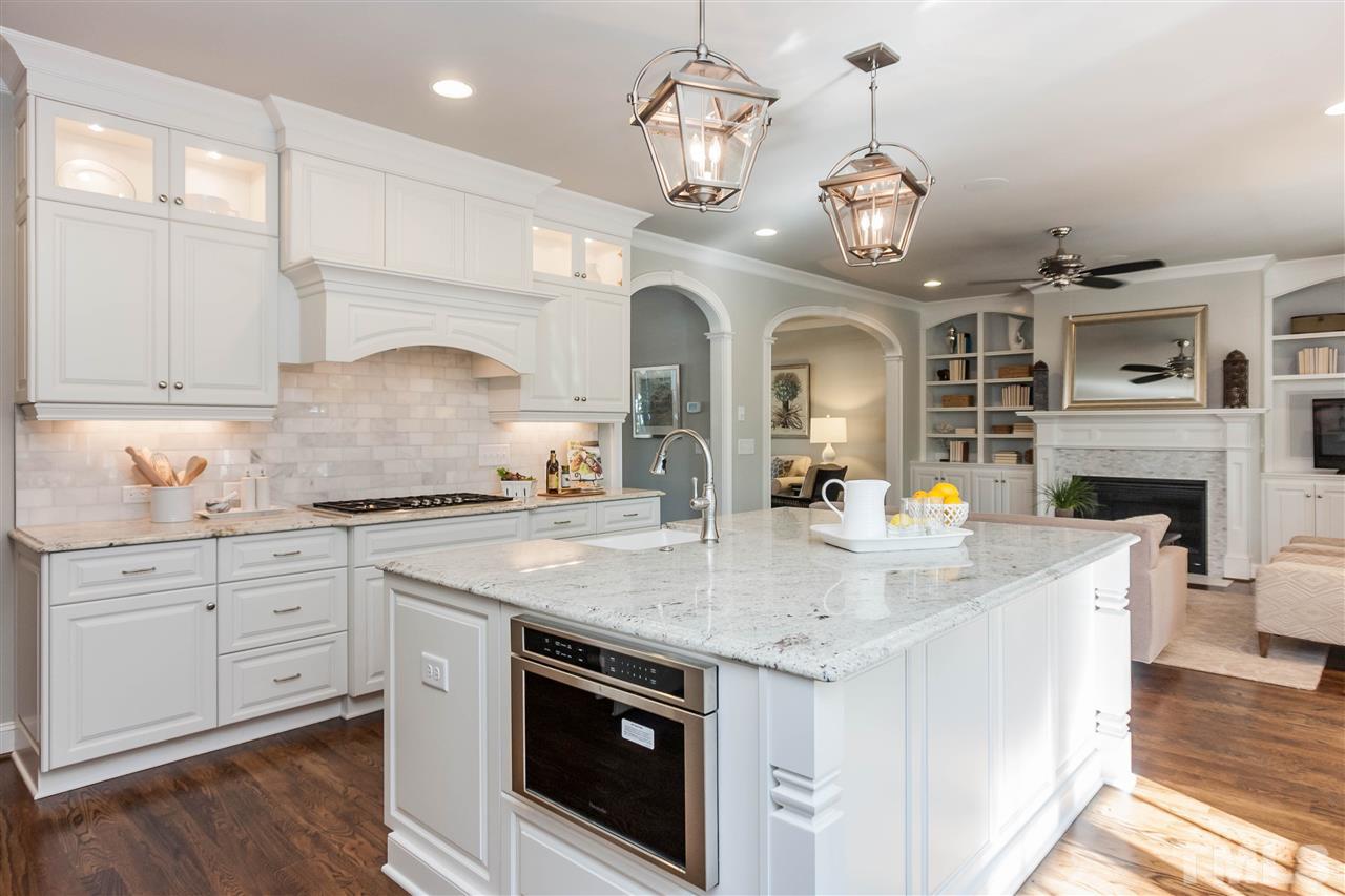 3106 Ashel Street Raleigh, NC 27612 - Photo 12 of 25 a kitchen with a stove center island a sink cabinets and wooden floor