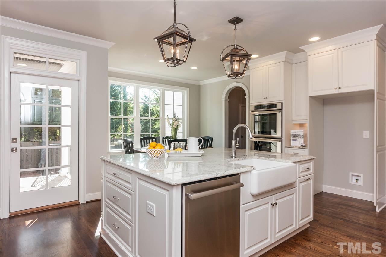 3106 Ashel Street Raleigh, NC 27612 - Photo 10 of 25 a kitchen with stainless steel appliances granite countertop a stove a sink a refrigerator and a dining table with wooden floor