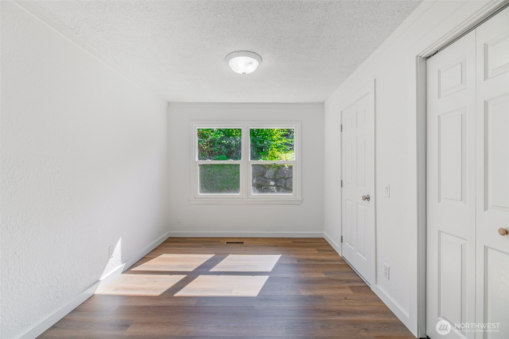 7051 South 125th Street Seattle, WA 98178 - Photo 12 of 32 a view of an empty room with wooden floor and a window