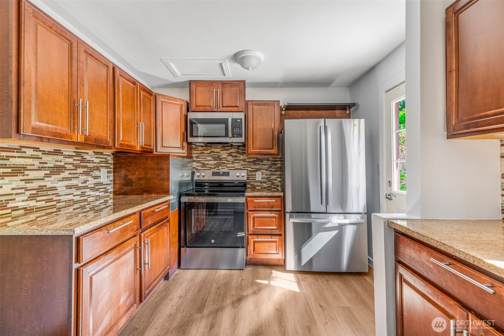 7051 South 125th Street Seattle, WA 98178 - Photo 5 of 32 a kitchen with granite countertop wooden floors appliances and sink
