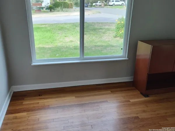 a view of an empty room with wooden floor and a window