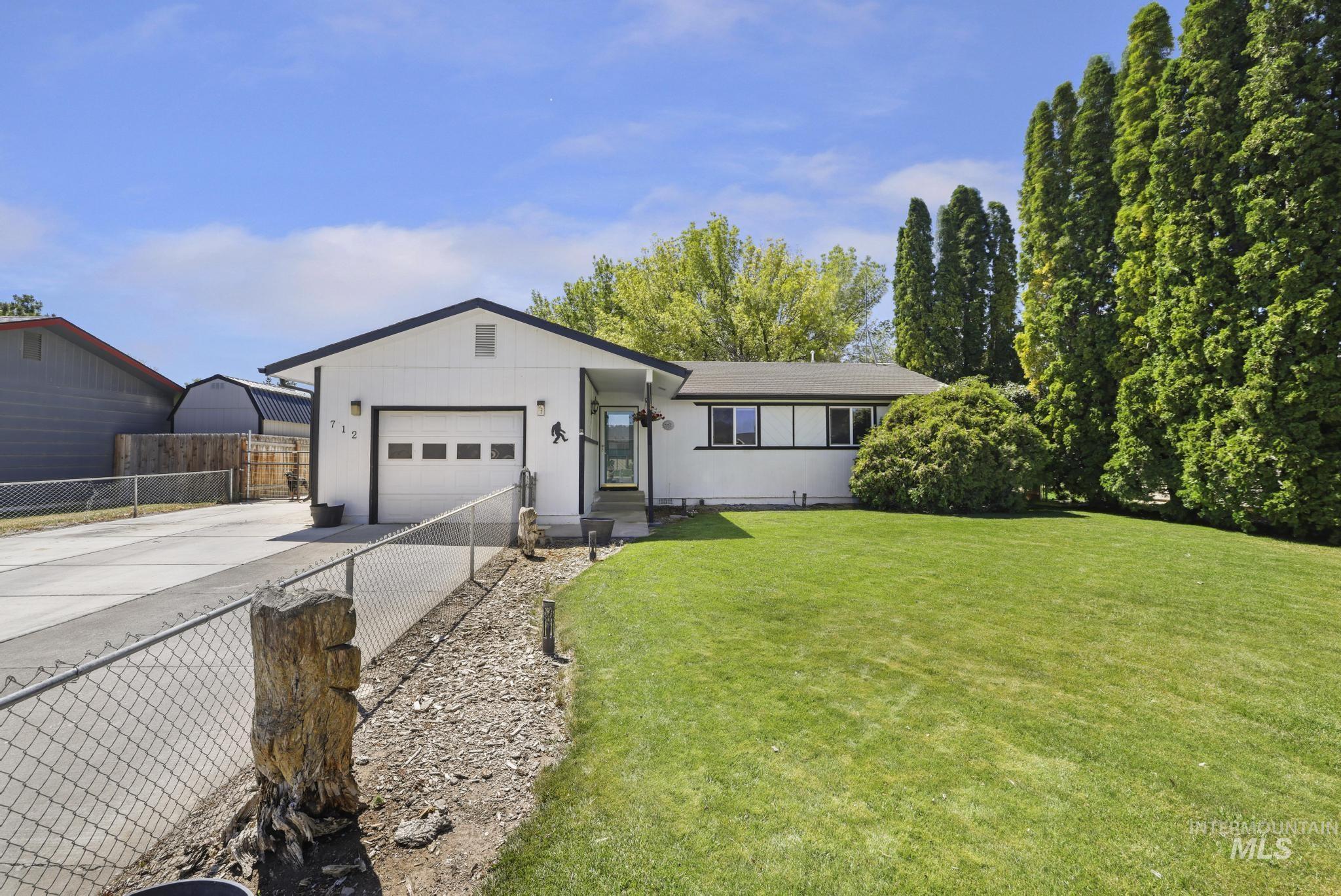 712 Locust Street Kimberly, ID 83341 - Photo 24 of 26 Expansive backyard featuring a manicured lawn, established shade trees, a gravel path with timber edging, a covered patio structure, and a fenced perimeter