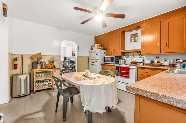 a open kitchen with stainless steel appliances kitchen island granite countertop a table chairs and a refrigerator
