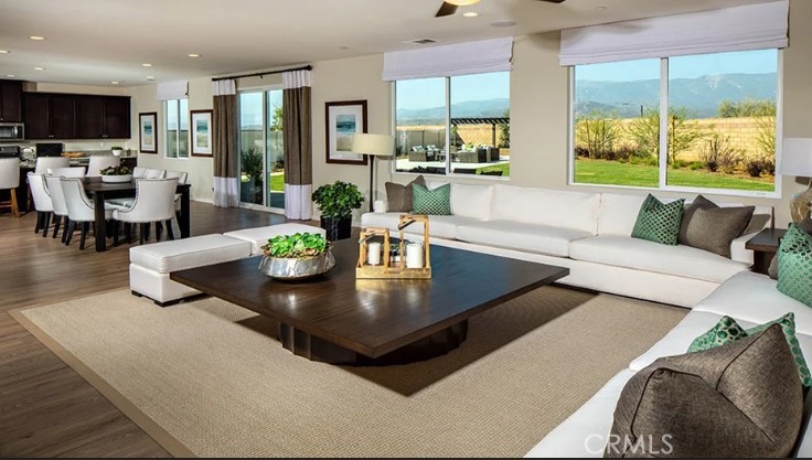 14073 Versimo Lane Beaumont, CA 92223 - Photo 7 of 20 a living room with large couches a coffee table and a flat screen tv with kitchen view