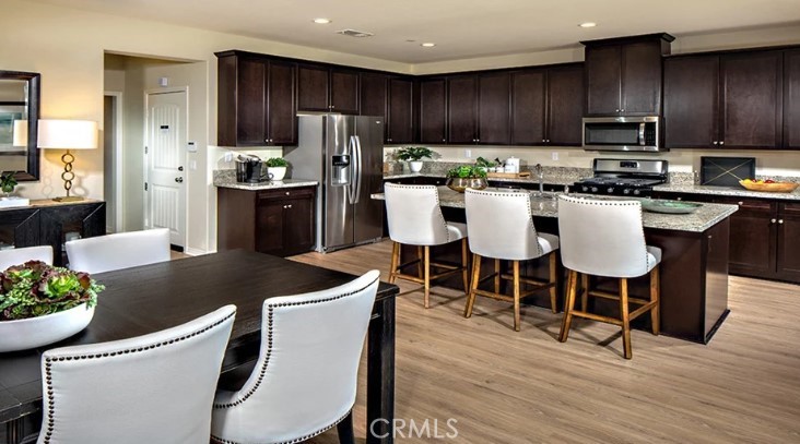 14073 Versimo Lane Beaumont, CA 92223 - Photo 9 of 20 a kitchen with stainless steel appliances kitchen island granite countertop a dining table chairs refrigerator and sink