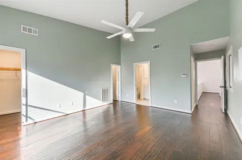 an empty room with wooden floor fan and windows