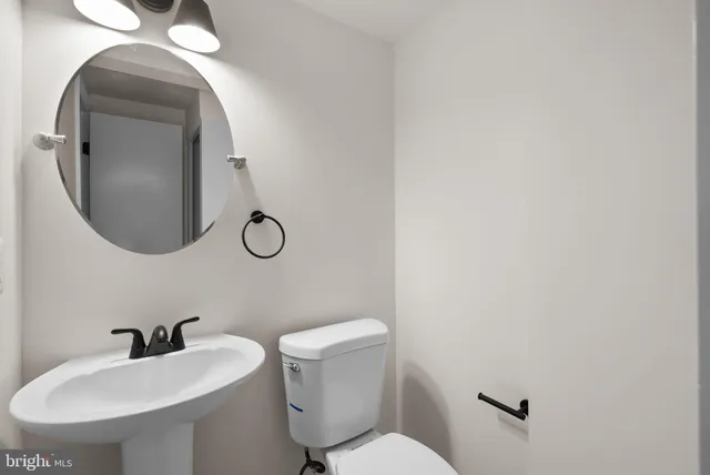 a bathroom with a toilet sink vanity and mirror