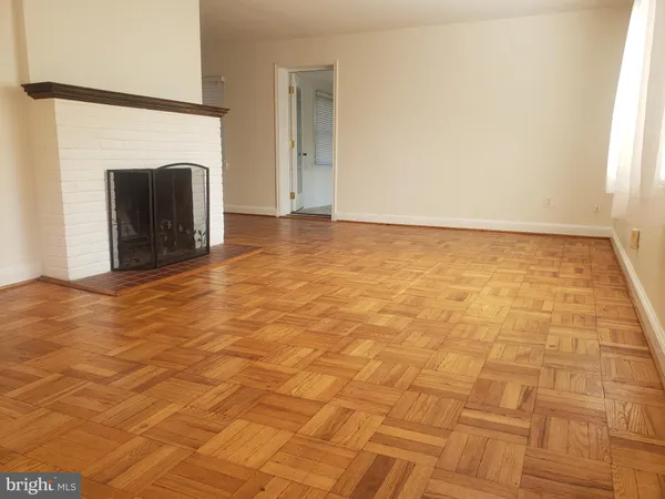 a view of an empty room with wooden floor and a fireplace