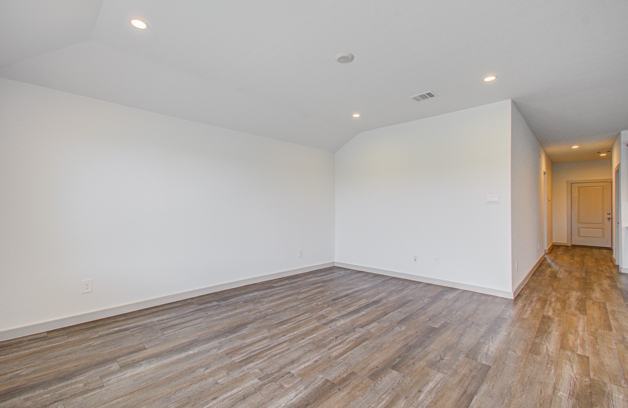 7903 Wrangler Shack Lane Rosharon, TX 77583 - Photo 20 of 29 Discover a spacious, inviting room with elegant wood-style flooring, neutral walls, and sophisticated recessed lighting, seamlessly connected to the rest of the home through an adjacent hallway.