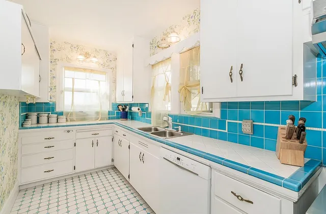 a kitchen with a sink dishwasher a stove and white cabinets