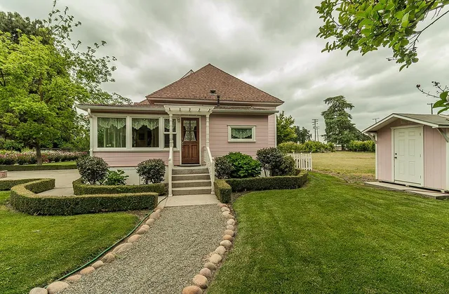 a front view of a house with garden and trees