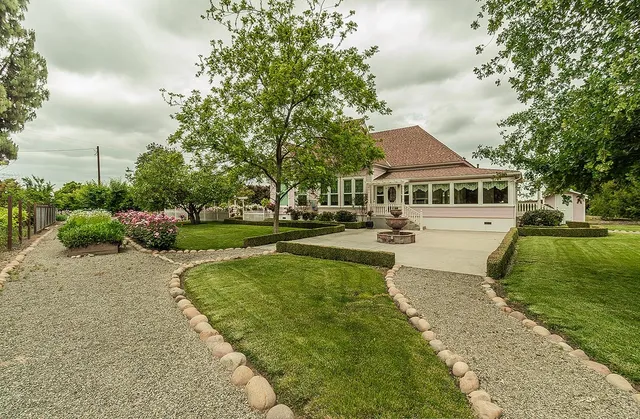 a front view of a house with a garden and trees