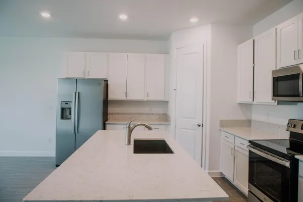 a kitchen with a refrigerator a stove and white cabinets