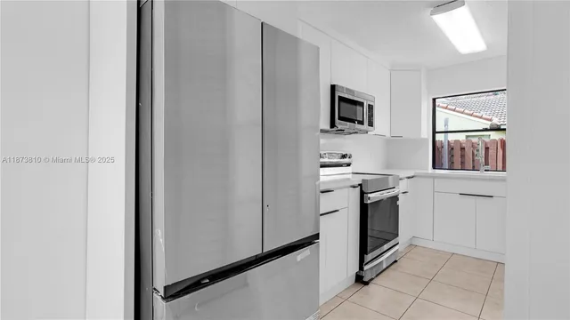 a kitchen with white cabinets and window