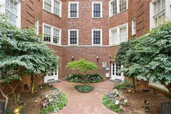 a front view of a multi story residential apartment building with yard and green space