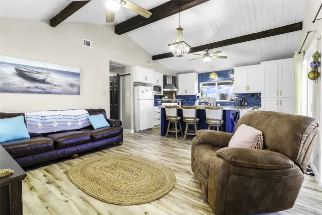 a kitchen with stainless steel appliances kitchen island granite countertop a dining table chairs and a refrigerator