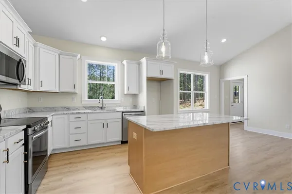 a kitchen with stainless steel appliances granite countertop a stove top oven a sink dishwasher a refrigerator and white cabinets with wooden floor