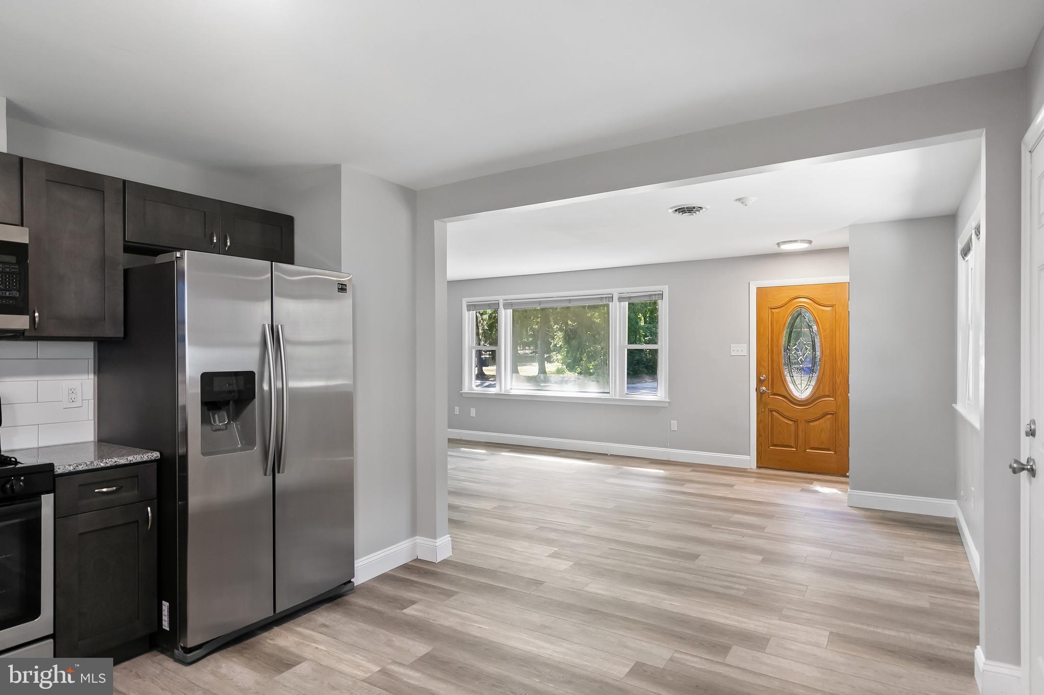 405 Hamilton Road Glassboro, NJ 08028 - Photo 11 of 28 a view of a refrigerator in kitchen and an empty room with wooden floor windows