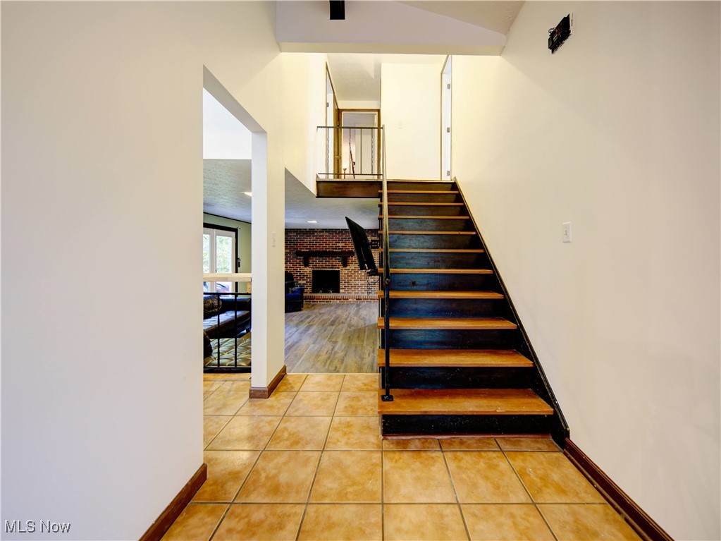 8075 Mulberry Road Chesterland, OH 44026 - Photo 22 of 38 Staircase featuring a fireplace, tile patterned flooring, and brick wall