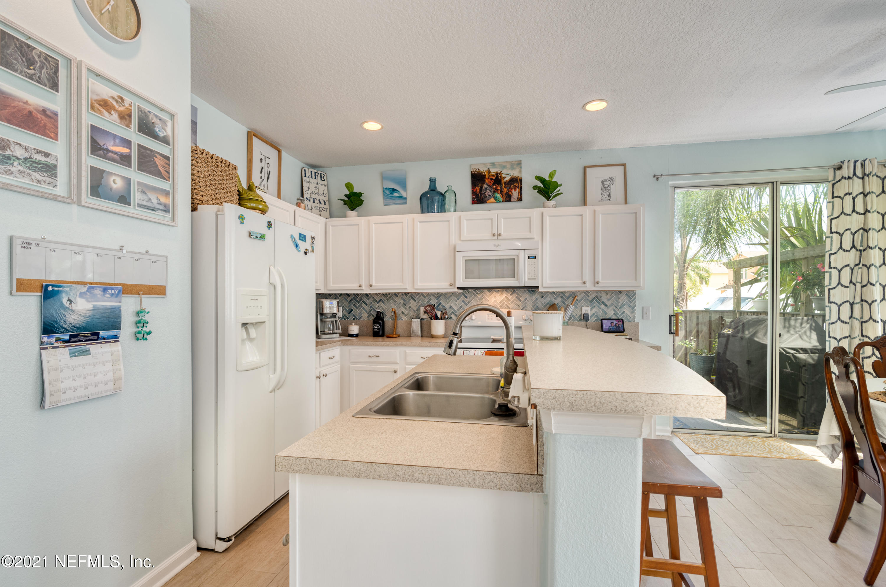 167 Bay Bridge Drive St. Augustine, FL 32080 - Photo 20 of 32 a open kitchen with a refrigerator a stove top oven a sink a dining table and chairs with the large window