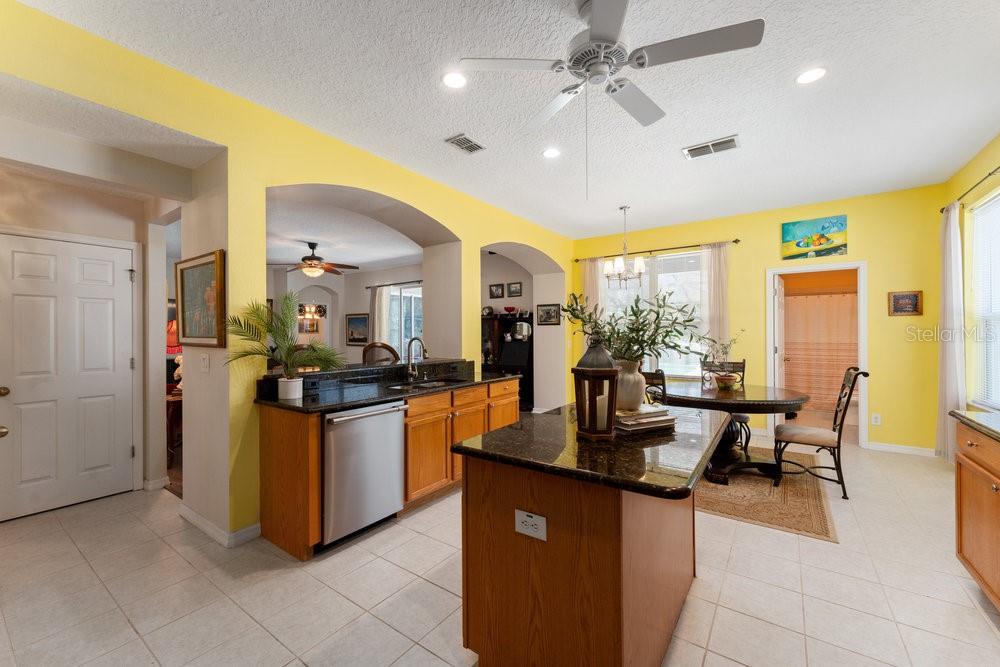 3463 Creek Run Lane Eustis, FL 32736 - Photo 28 of 83 a kitchen with stainless steel appliances granite countertop a refrigerator a sink dishwasher a oven and a dining table with wooden floor