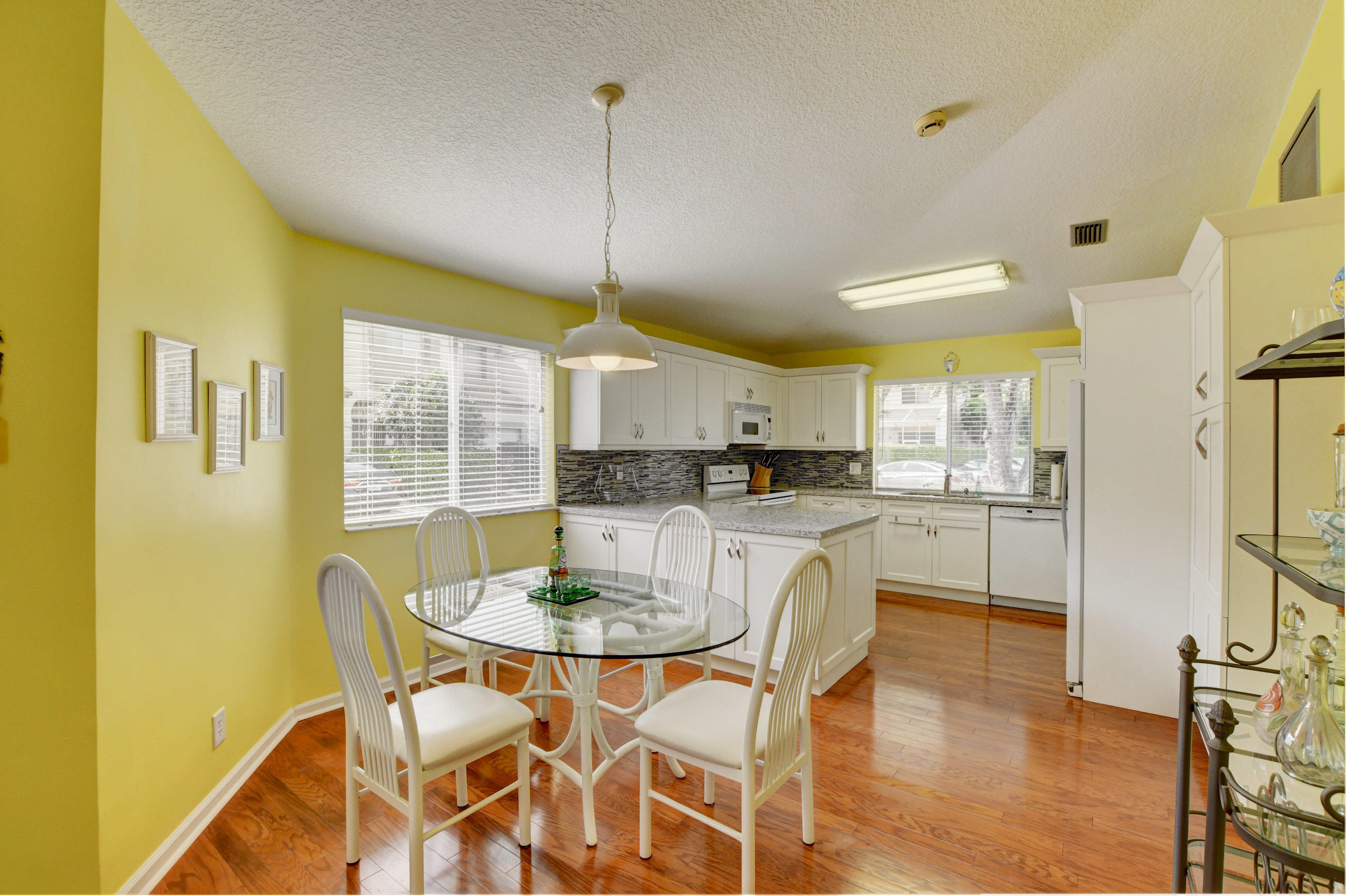 6746 Via Regina Boca Raton, FL 33433 - Photo 6 of 25 a kitchen with stainless steel appliances kitchen island granite countertop a dining table chairs and white cabinets
