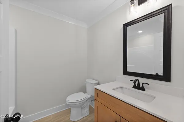 a bathroom with a granite countertop sink vanity mirror and toilet