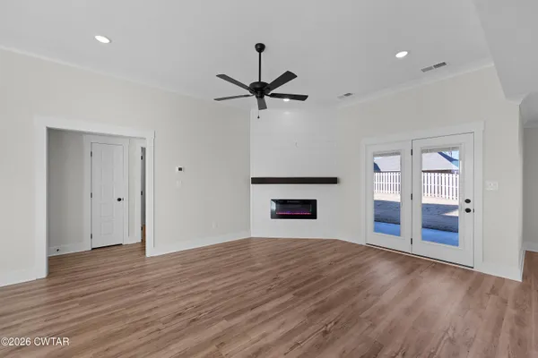 a view of an empty room with window and wooden floor