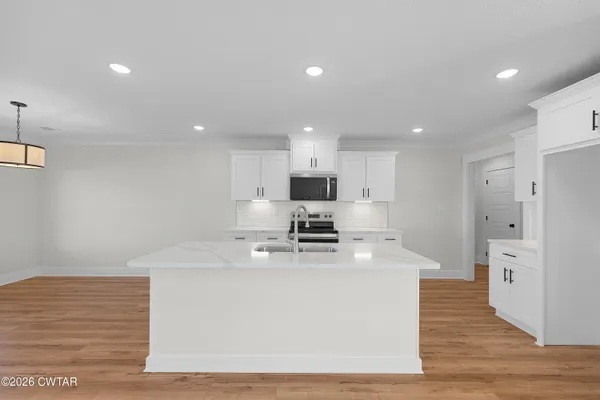 a kitchen with stainless steel appliances a white stove top oven and white cabinets