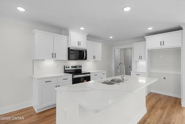 a kitchen with granite countertop a sink stainless steel appliances and white cabinets