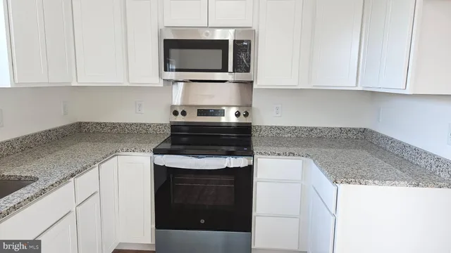 a kitchen with stainless steel appliances granite countertop white cabinets granite counter tops and a hard wood floors