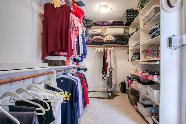 a view of walk in closet with clothes and shoes