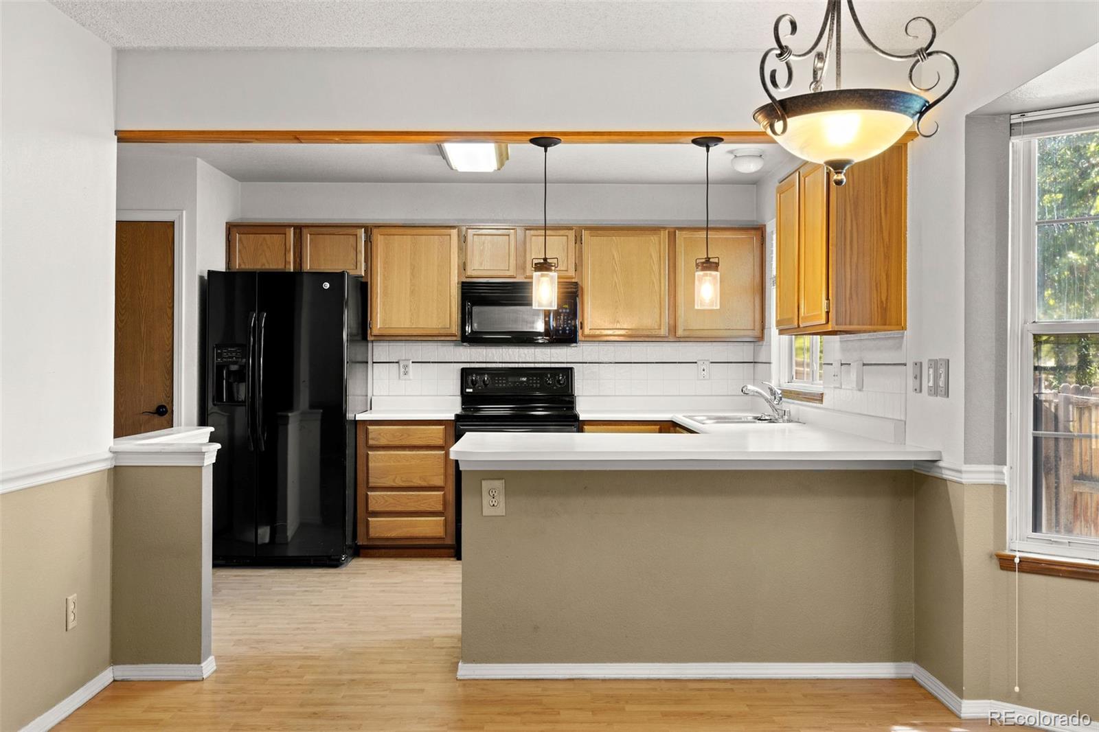 8536 Union Circle Arvada, CO 80005 - Photo 8 of 26 a kitchen with kitchen island a counter top space a sink refrigerator and cabinets