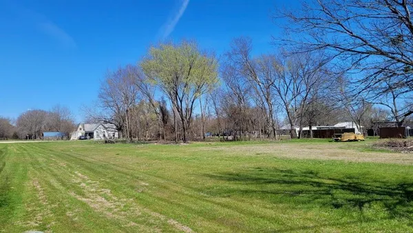 a grassy field with trees in the background