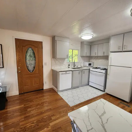 a kitchen with granite countertop a refrigerator a stove a sink and a dining table with wooden floor