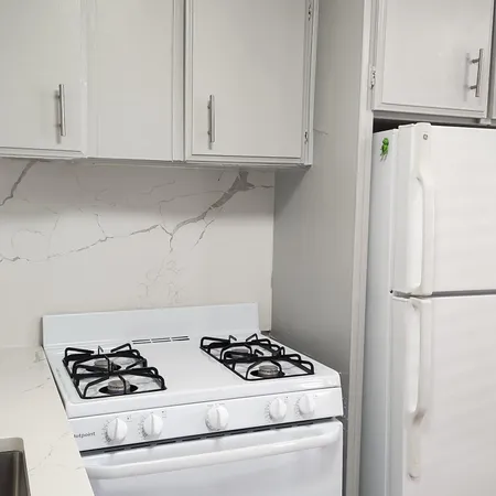 a kitchen with white cabinets and white stove