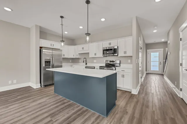 a large kitchen with stainless steel appliances and wooden floor