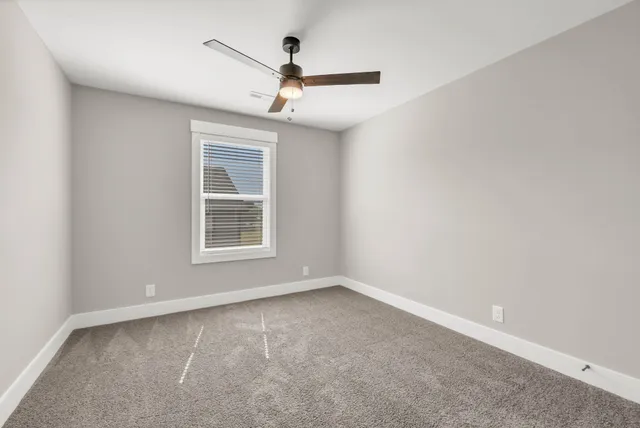 an empty room with a ceiling fan and windows