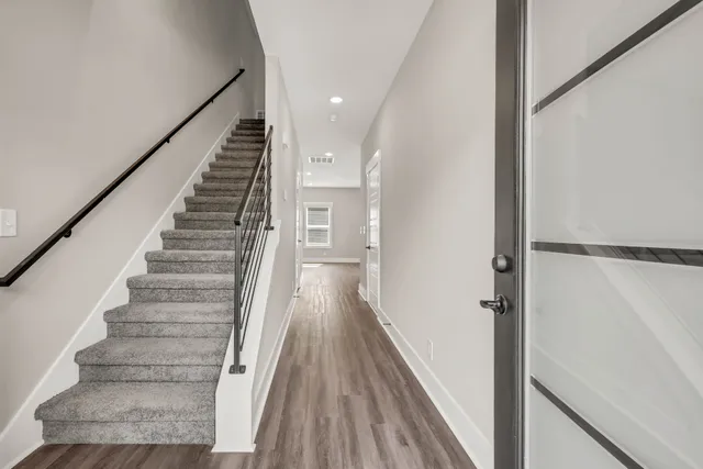 a view of a hallway with wooden floor and staircase