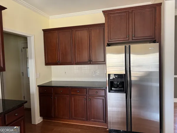 a kitchen with granite countertop wooden cabinets and refrigerator