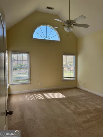 an empty room with windows and fan