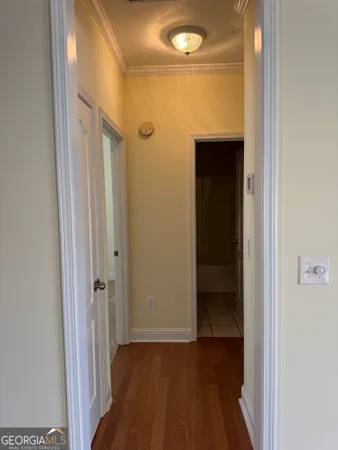 a view of a hallway with wooden floor and a bathroom
