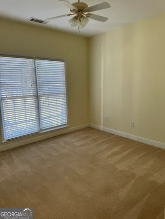 an empty room with a ceiling fan and window