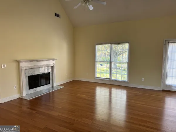 an empty room with wooden floor fireplace and windows