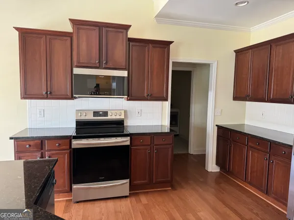 a kitchen with granite countertop wooden cabinets and stainless steel appliances