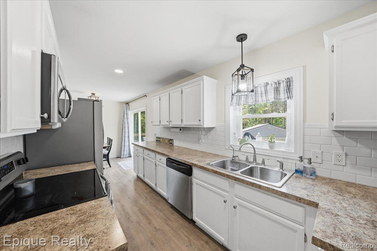 12272 East Mt Morris Road Davison, MI 48423 - Photo 12 of 39 Kitchen featuring white cabinetry, wood-finish flooring, subway tile backsplash, stainless steel appliances, and a double basin sink